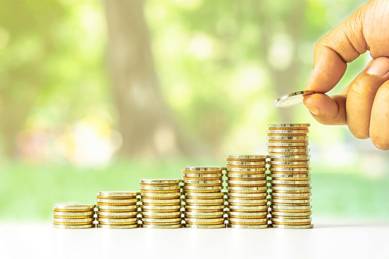 hand placing coin at top of stacks trending upward