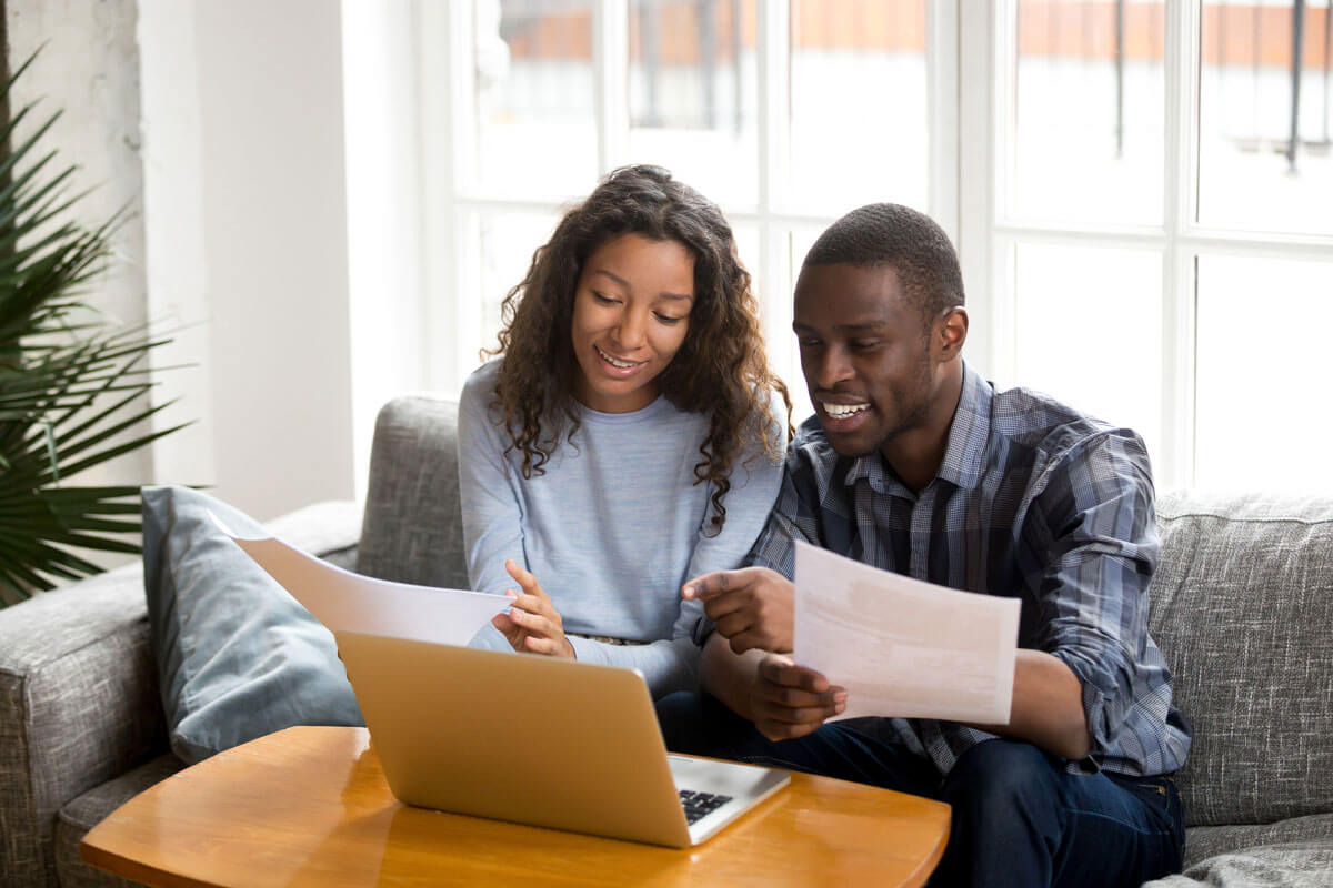 Couple at home checking computer, reviewing documents